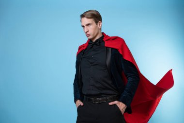 Takım elbiseli, kırmızı pelerinli, güçlü ve kendinden emin bir süper kahraman.,