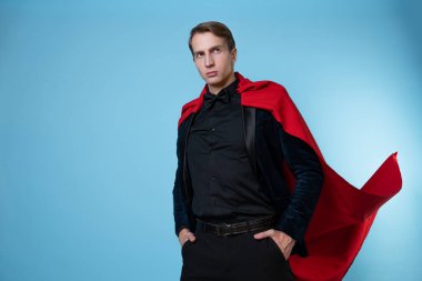 Takım elbiseli, kırmızı pelerinli, güçlü ve kendinden emin bir süper kahraman.,