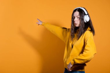 Müzik severler müzikten hoşlanır. Beyaz kablosuz kulaklıklı sarı kapüşonlu genç bir kadın.,