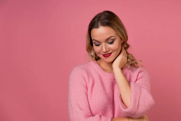 Giovane donna attraente in un caldo maglione rosa su uno sfondo rosa, — Foto Stock