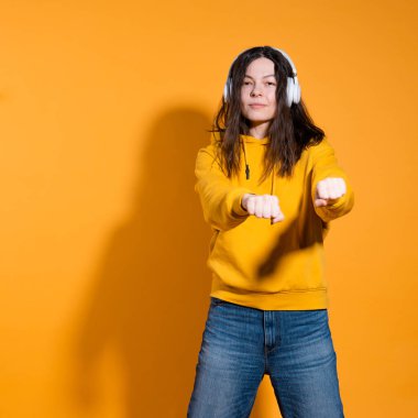 Mutlu dans müziği severler. Beyaz kablosuz kulaklıklı sarı kapüşonlu genç bir kadın.,