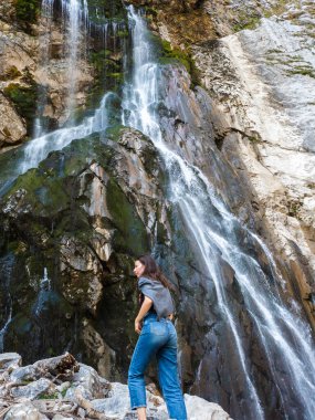 Ormanda turizm, dağ şelalesinin arka planında genç bir kadın.,