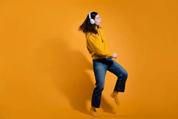 Feliz amante de la música bailable. Una joven con capucha amarilla y auriculares inalámbricos blancos, — Foto de Stock