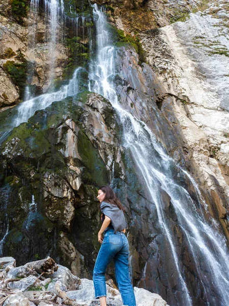 Ormanda turizm, dağ şelalesinin arka planında genç bir kadın.,