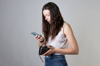 Akıllı telefonunuzdaki uygulamadan banka hesabınızı kontrol edin. Cüzdanı ve telefonu olan genç bir kadın.