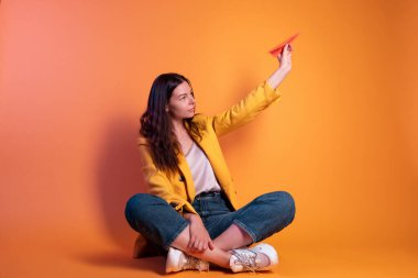 Kağıt uçak, rüya yolculuğu konsepti. Sarı elbiseli esmer kadın.