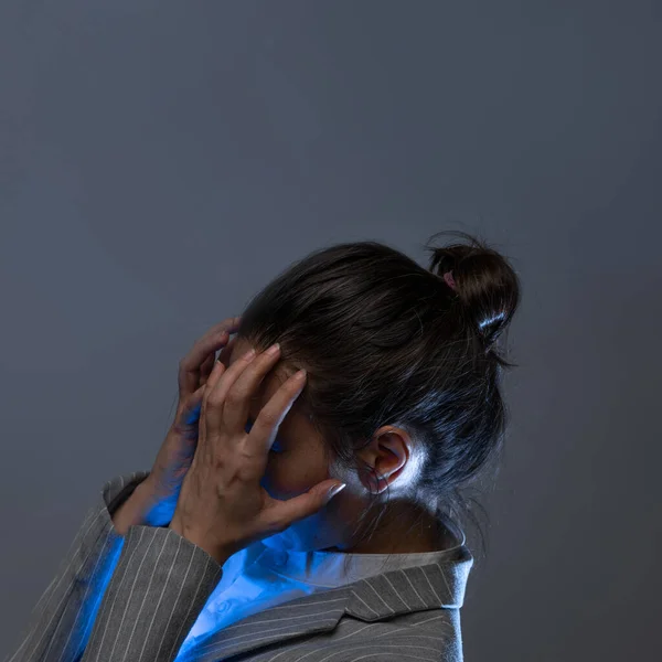 Голова болела из-за переутомления на работе, молодая женщина в деловом костюме сжала голову руками, — стоковое фото