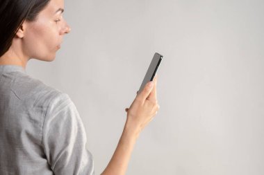 Kadın gözünün önünde akıllı telefon tutuyor, uygulamayı kullanıyor ya da fotoğraf çekiyor..