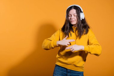 Mutlu dans müziği severler. Beyaz kablosuz kulaklıklı sarı kapüşonlu genç bir kadın.,