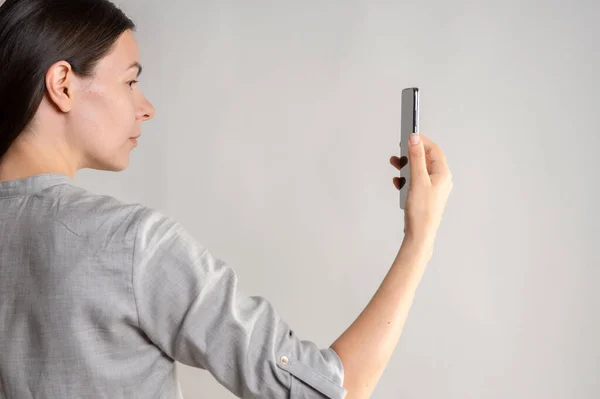 Γυναίκα κατέχει ένα smartphone μπροστά από τα μάτια της, χρησιμοποιήστε την εφαρμογή ή τραβήξτε μια φωτογραφία. — Φωτογραφία Αρχείου
