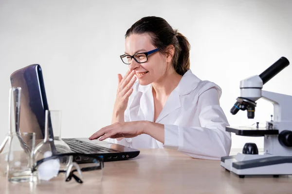 Mladá žena, laboratorní asistentka nebo badatel se směje při pohledu na notebook. — Stock fotografie