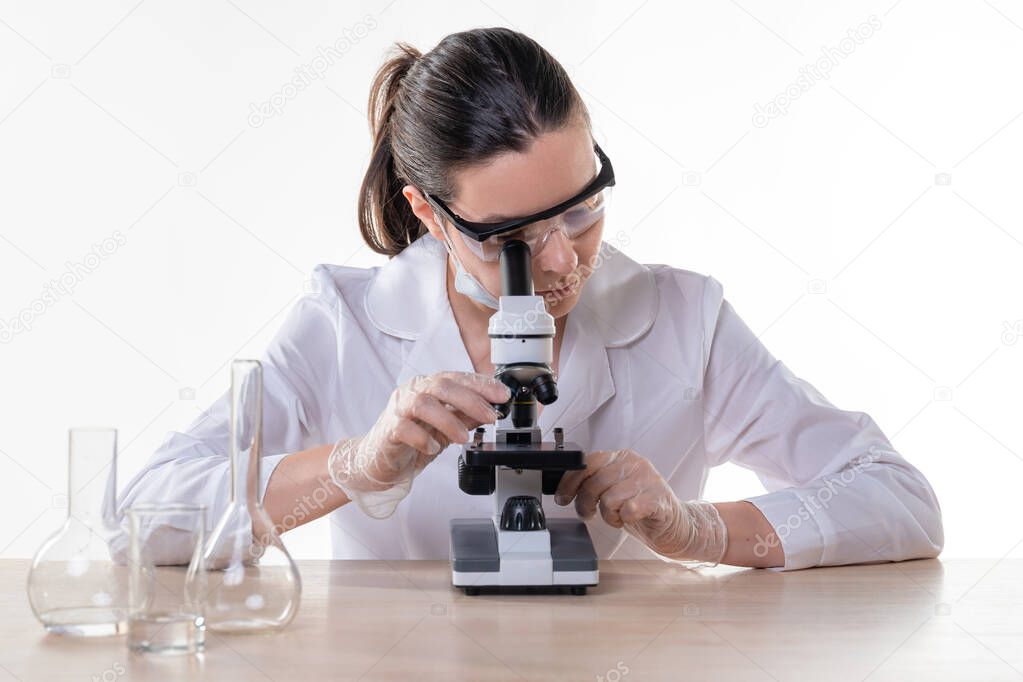 lab technician looks into the eyepiece of a microscope, a young female doctor