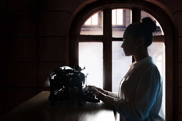 young beautiful woman author at a typewriter, writes a text,