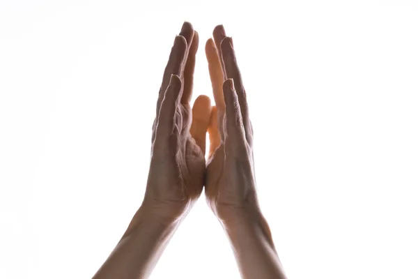 Des mains priantes sur un fond blanc. Lumière d'en haut. Les mains jointes dans la prière. Les gestes de la main — Photo