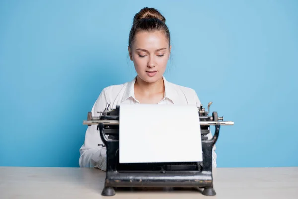 Joven escritora en una máquina de escribir, escribe un texto. Un escritor en una mesa con una máquina de escribir vintage — Foto de Stock