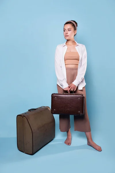 Słodka młoda kobieta w letnich spodniach i białej koszuli trzyma walizkę w rękach — Zdjęcie stockowe