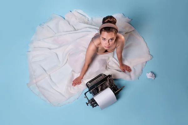 若いロマンチックな女性はタイプライターの作家ですふわふわの白いスカートの床に座って — ストック写真