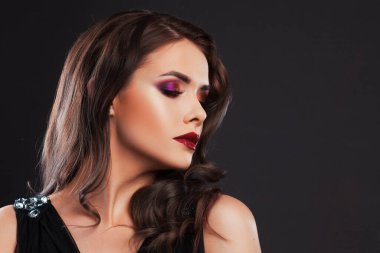 Şık bir akşam görünümlü, güzel, genç bir esmer. Kırmızı dudaklar ve göz farı, dalgalı saç stili.