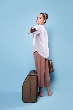 Hadi tatile çıkalım. Yazlık pantolonlu ve beyaz gömlekli hoş bir kadın elinde bir evrak çantası tutuyor.