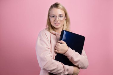 Gözlüklü ve elinde dizüstü bilgisayarı olan bir öğrenci pembe kazaklı genç, sevimli bir sarışın.