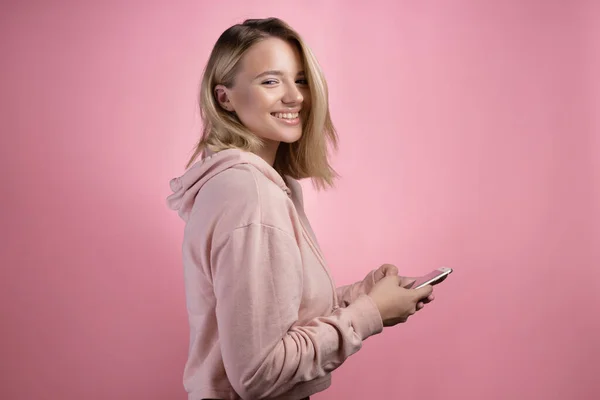 Uma jovem loira com um corte de cabelo quadrado, usa um smartphone para se comunicar, escrever mensagens em um bate-papo. — Fotografia de Stock