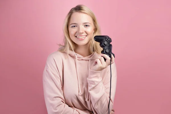 Okouzlující blonďatý hráč. Mladá usměvavá žena v růžové mikině drží joystick — Stock fotografie