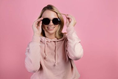 Koyu renk güneş gözlüğü takan sarı saçlı güzel bir genç kadın..