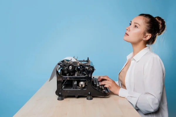 Jonge vrouw auteur bij een typemachine, schrijft een tekst. Een schrijver aan tafel met een vintage typemachine — Stockfoto