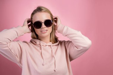 Sarı saçlı, güneş gözlüklü güzel bir kadın kameraya bakıyor.