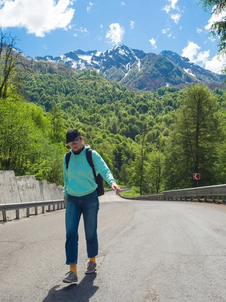 Дорога в горах. Молодая женщина в синей толстовке идет вперед. — стоковое фото