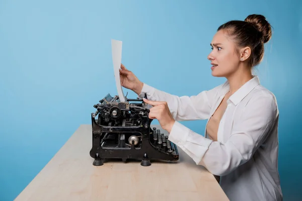 Jonge vrouw schrijver op een typemachine is geschokt door wat ze schreef, — Stockfoto