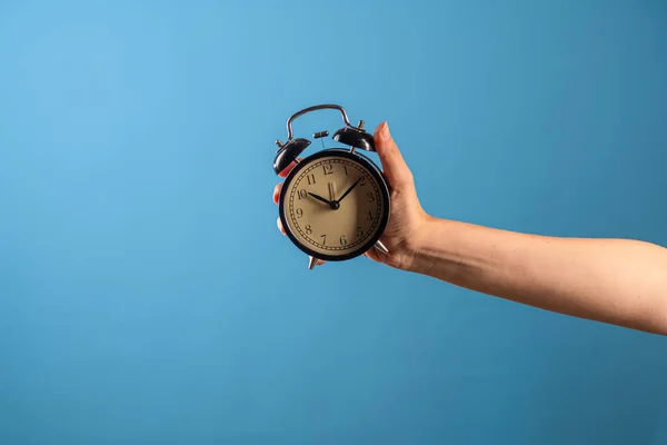 Despacha-te, está na hora de agir, conceito. Uma mão feminina segura um despertador vintage, — Fotografia de Stock