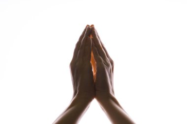 Beyaz bir arka planda dua eden eller. Yukarıdan gelen ışık. Ellerin duayla bağlandı. El hareketleri