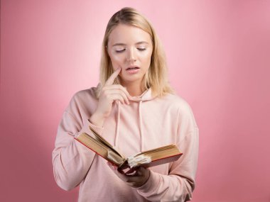 Elinde kitap olan çekici genç bir kız öğrenci. Pembe kapüşonlu genç, tatlı bir sarışın.