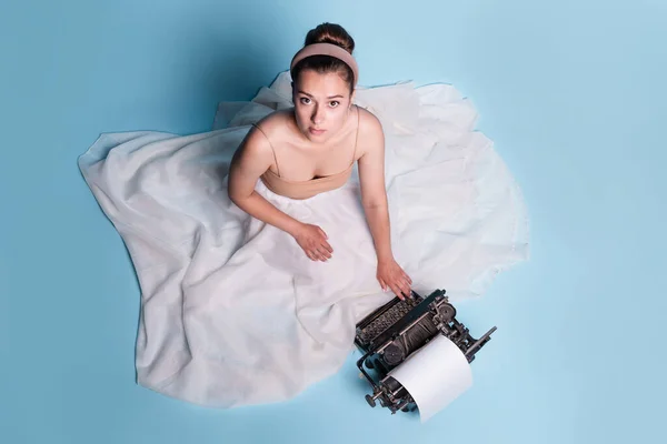 Tânără femeie romantică este un autor la o mașină de scris, așezat pe podea într-o fustă albă pufoasă — Fotografie, imagine de stoc