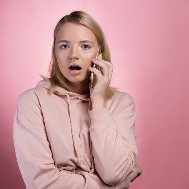 Telefonu olan şaşırmış genç bir kadın. Şok edici telefon konuşması.,