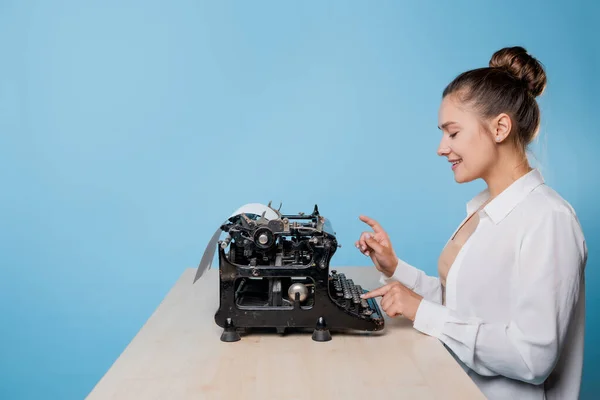 Joven escritora en una máquina de escribir, está inspirada, es apasionada por escribir un texto. — Foto de Stock
