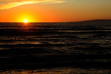 Güneşli deniz günbatımında bazı bulutlarla