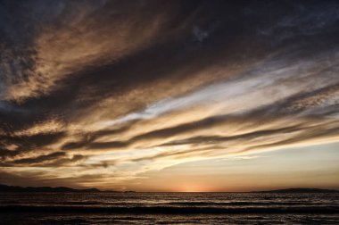 Güneşli deniz günbatımında bazı bulutlarla