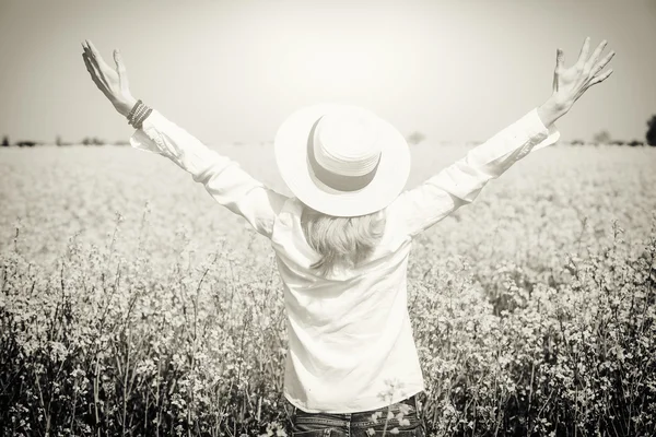 Szczęśliwy, piękna dziewczyna przed Rzepakowego pola w rozkwicie z otwartej ręce pozdrowienie słoneczny wiosenny dzień, wolności i dobrobytu koncepcja — Zdjęcie stockowe