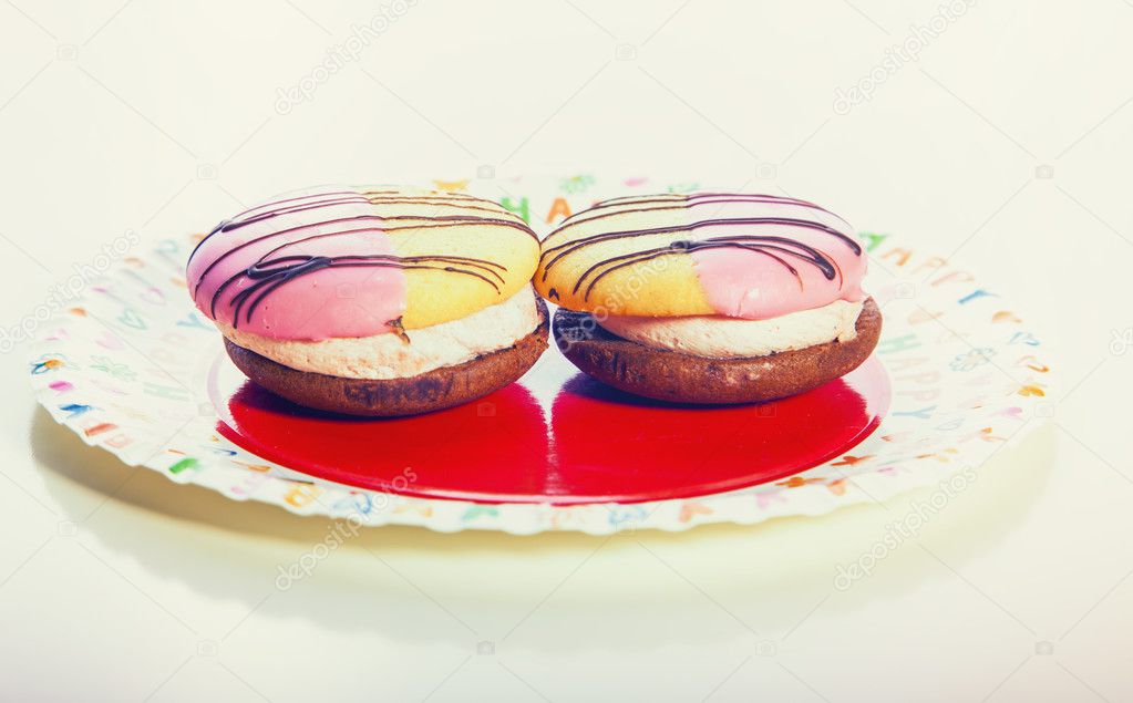 two colorful cakes with cream on the top on white background