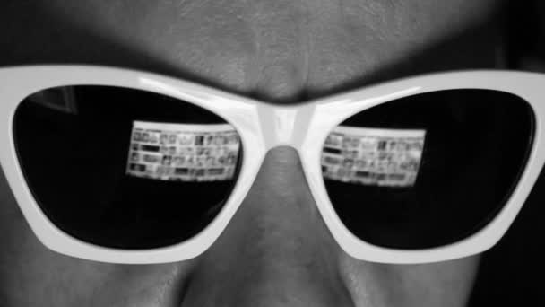 Człowiek w okularach surfing internet na komputerze przenośnym w nocy, człowiek przeglądanie zdjęć na ekranie z odbiciem na okulary przeciwsłoneczne — Wideo stockowe
