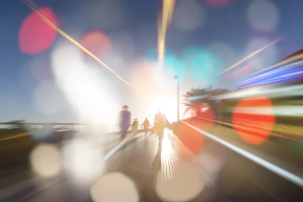 People in bokeh, sunset street with palms — Stock Photo, Image