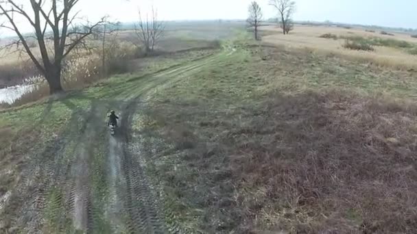 Motorrijder rijden op een veld in het platteland. — Stockvideo