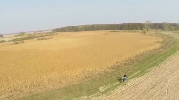 Motorcyklist ridning på ett fält på landsbygden. — Stockvideo