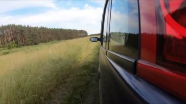 Araba gün batımından önce vahşi doğada off-road yapar. Kamera aracın dışındadır ve ileri doğru yönelir..