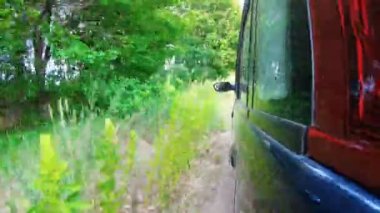 Araba gün batımından önce vahşi doğada off-road yapar. Kamera aracın dışındadır ve ileri doğru yönelir..