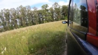 Araba gün batımından önce vahşi doğada off-road yapar. Kamera aracın dışındadır ve ileri doğru yönelir..