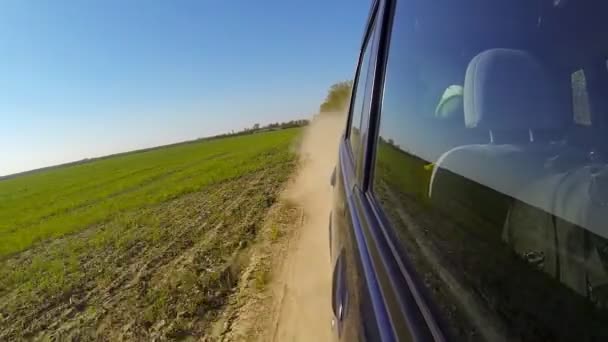 Conduce rápido un coche en el campo. La cámara está fuera y apuntó hacia atrás . — Vídeo de stock