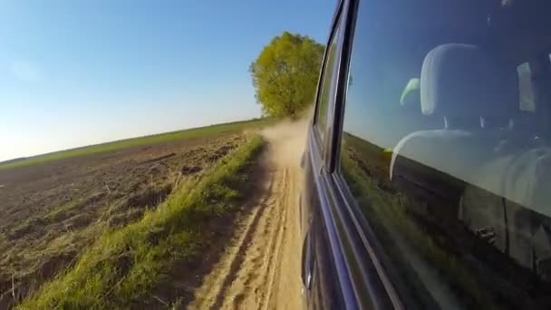 Snel besturen van een auto op het platteland. De camera is buiten en gericht terug. — Stockvideo